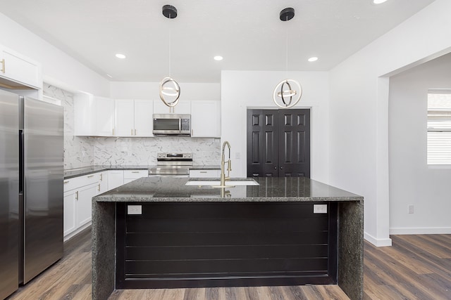 kitchen with hanging light fixtures, appliances with stainless steel finishes, an island with sink, and sink