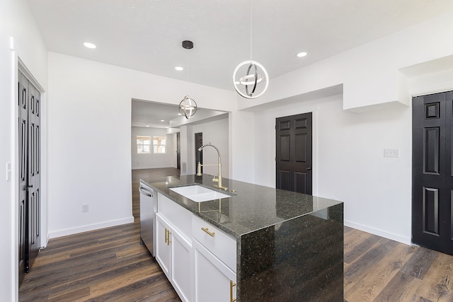 kitchen featuring hanging light fixtures, dark stone counters, dishwasher, dark hardwood / wood-style flooring, and sink