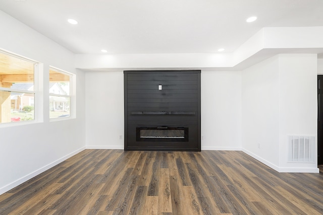 unfurnished living room featuring dark hardwood / wood-style floors and a large fireplace