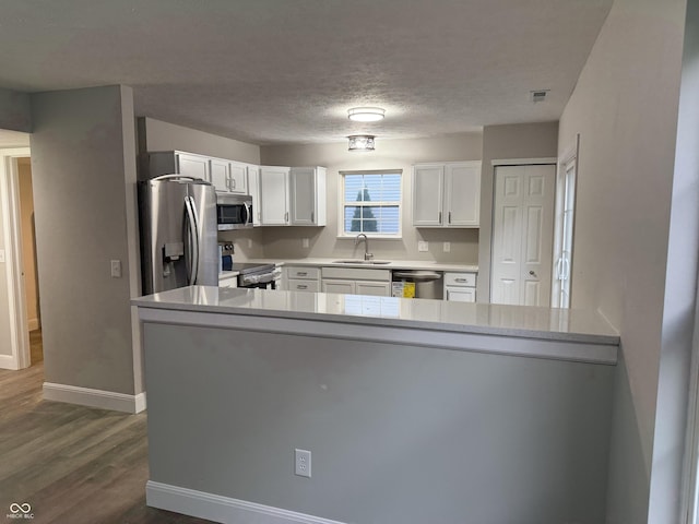 17902 Cristin Way, Westfield, IN 46062 - kitchen with appliances with stainless steel finishes, white cabinetry, dark wood-type flooring, a peninsula, and a textured ceiling