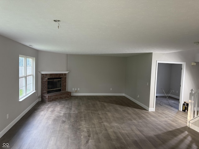 17902 Cristin Way, Westfield, IN 46062 - unfurnished living room featuring dark wood-type flooring, a brick fireplace, and a textured ceiling