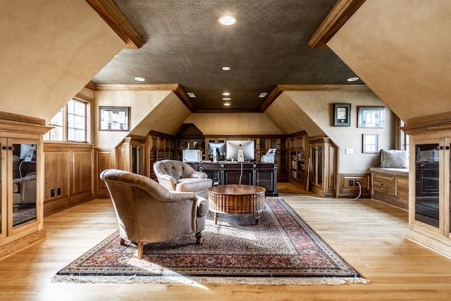 interior space featuring lofted ceiling, light hardwood / wood-style flooring, crown molding, and wood walls