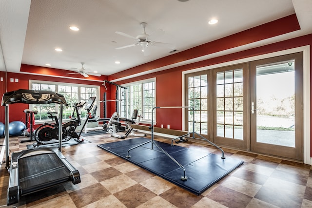 gym with ceiling fan, a tray ceiling, and french doors