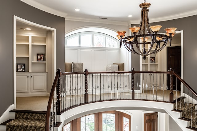 stairway with carpet flooring, crown molding, and a notable chandelier