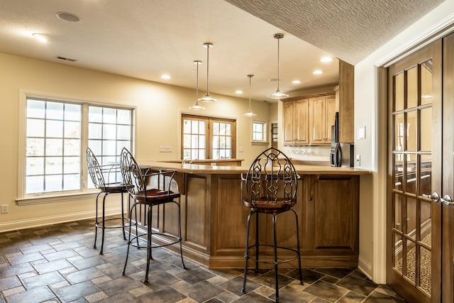 kitchen with kitchen peninsula, a kitchen breakfast bar, decorative light fixtures, and a wealth of natural light