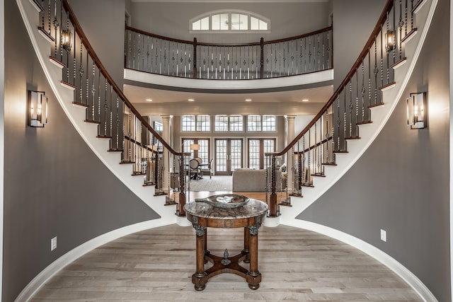 foyer entrance featuring decorative columns, hardwood / wood-style floors, and a high ceiling