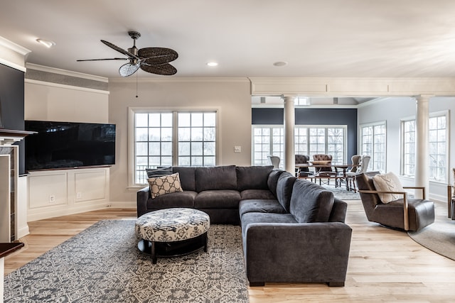 living room featuring ceiling fan, light wood-type flooring, crown molding, and ornate columns