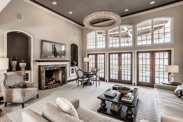 carpeted living room with a towering ceiling, a fireplace, a wealth of natural light, and french doors