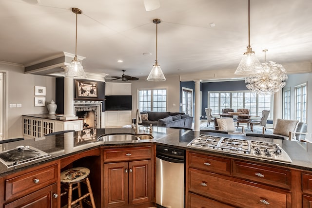 kitchen with ornate columns, ceiling fan with notable chandelier, stainless steel gas cooktop, sink, and hanging light fixtures