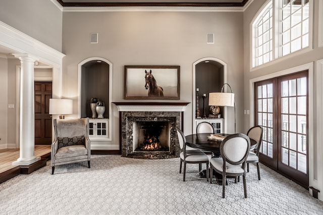 dining room with ornate columns, french doors, a high end fireplace, and ornamental molding