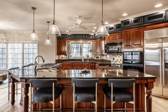 kitchen featuring a large island, black appliances, and decorative light fixtures