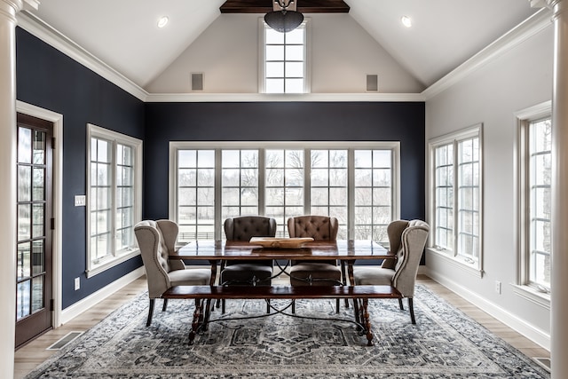 dining space featuring decorative columns, crown molding, high vaulted ceiling, and hardwood / wood-style flooring