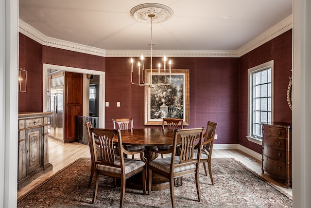 dining space with ornamental molding, light hardwood / wood-style floors, and an inviting chandelier