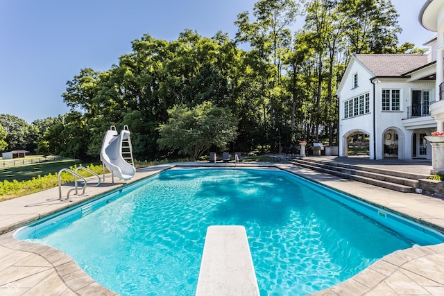 view of pool featuring a diving board, a patio, and a water slide