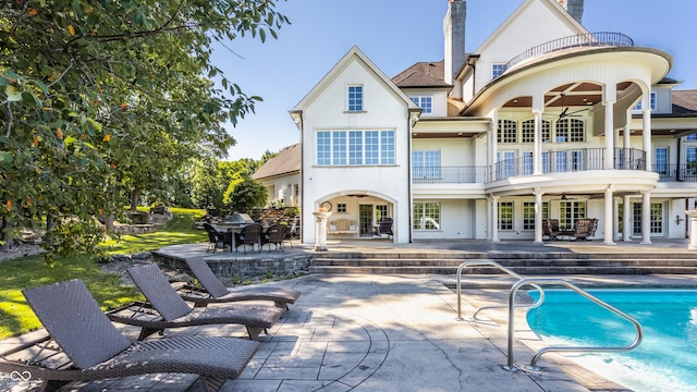 rear view of house with ceiling fan, a patio area, a balcony, and french doors