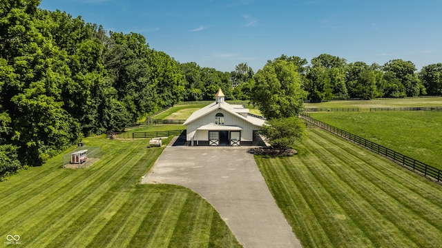 view of community featuring a lawn, a rural view, and an outdoor structure