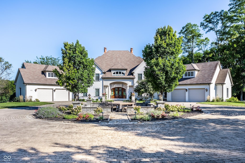 view of front of home with a garage, french doors, decorative driveway, and a residential view