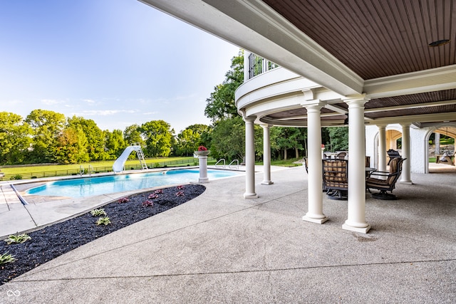 view of pool with a water slide and a patio