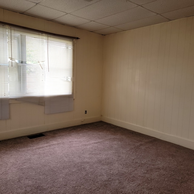 carpeted empty room with a drop ceiling