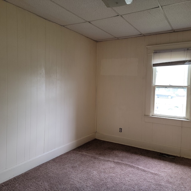 empty room with a paneled ceiling and carpet floors