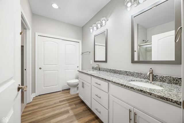 bathroom featuring walk in shower, wood-type flooring, vanity, and toilet