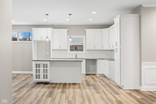 kitchen with light hardwood / wood-style flooring, stone counters, decorative light fixtures, and white cabinets