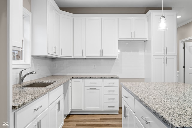 kitchen featuring decorative light fixtures, white cabinetry, sink, and light hardwood / wood-style floors