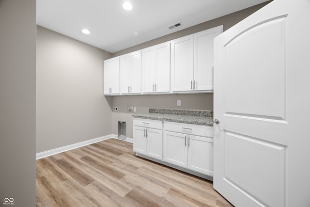 clothes washing area featuring hookup for a washing machine, cabinets, and light hardwood / wood-style floors