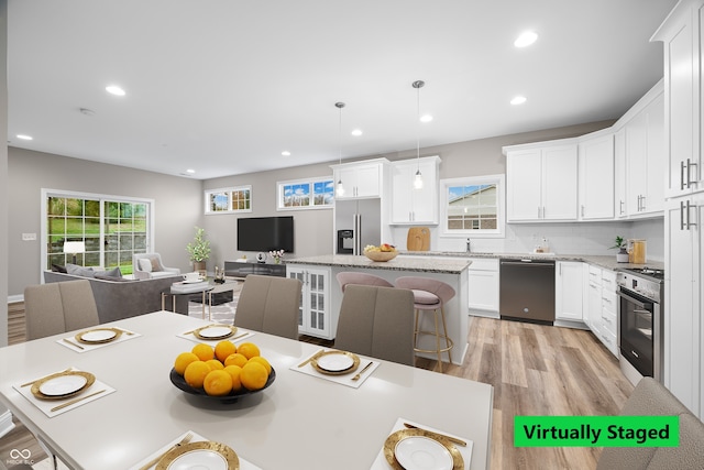 kitchen featuring white cabinetry, appliances with stainless steel finishes, hanging light fixtures, and a kitchen island