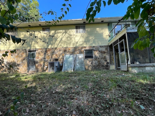 view of side of home with a balcony, central air condition unit, and a sunroom