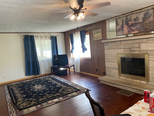 living room with a fireplace, ceiling fan, a healthy amount of sunlight, and wooden walls