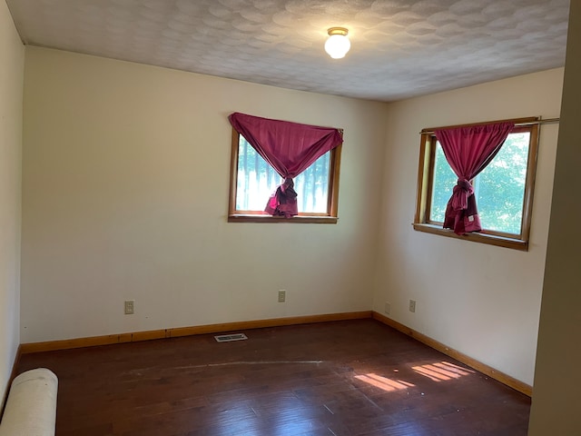 unfurnished room with a textured ceiling and dark hardwood / wood-style flooring