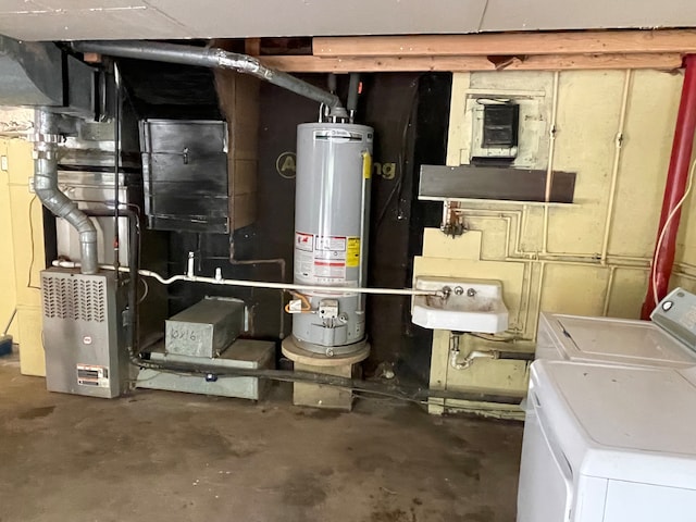 utility room with water heater, independent washer and dryer, and sink