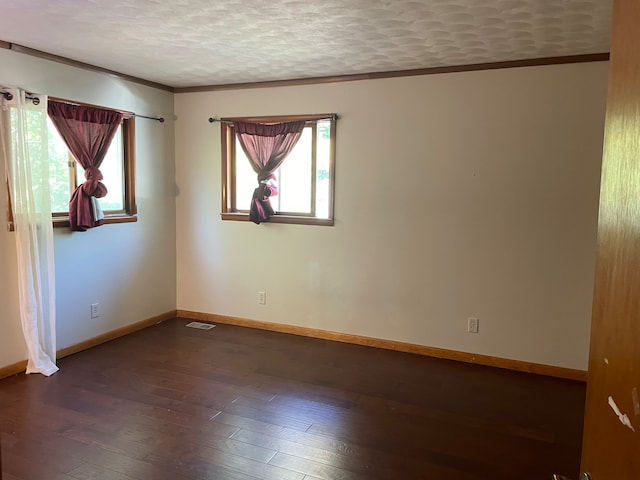 empty room with dark hardwood / wood-style flooring, a textured ceiling, a wealth of natural light, and crown molding