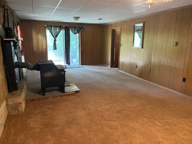 interior space featuring wooden walls, a wood stove, and carpet flooring