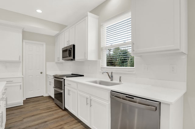 kitchen with stainless steel appliances, tasteful backsplash, sink, white cabinets, and dark hardwood / wood-style flooring