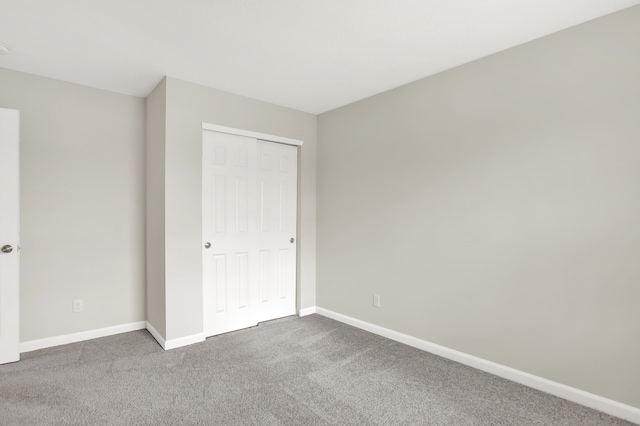 unfurnished bedroom featuring dark colored carpet and a closet