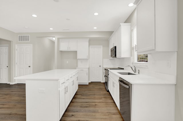 kitchen with appliances with stainless steel finishes, sink, wood-type flooring, and white cabinetry