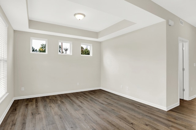 empty room with a tray ceiling and dark wood-type flooring