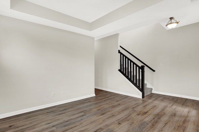 unfurnished room featuring a raised ceiling and dark hardwood / wood-style floors