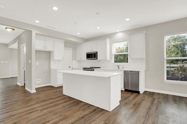 kitchen with dark hardwood / wood-style flooring, white cabinetry, appliances with stainless steel finishes, and a center island