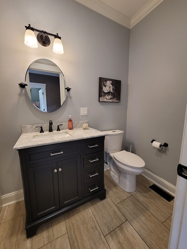 bathroom with vanity, toilet, ornamental molding, and hardwood / wood-style floors