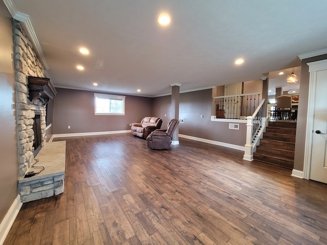 unfurnished room featuring a stone fireplace, ornamental molding, and dark wood-type flooring