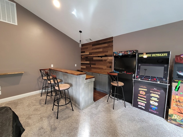 bar with wooden counters, hanging light fixtures, high vaulted ceiling, and wood walls