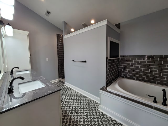 bathroom featuring vanity, a relaxing tiled tub, tile patterned flooring, and vaulted ceiling