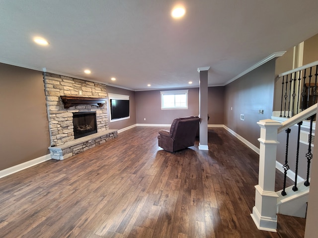 living room with crown molding, a stone fireplace, and dark hardwood / wood-style floors