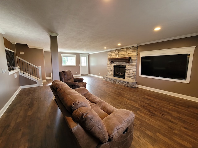 living room featuring a stone fireplace, ornamental molding, and dark wood-type flooring