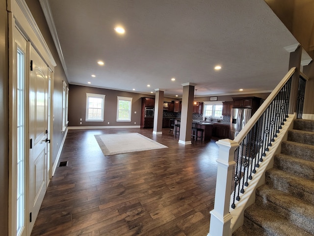 foyer entrance with a wealth of natural light, crown molding, and dark hardwood / wood-style flooring