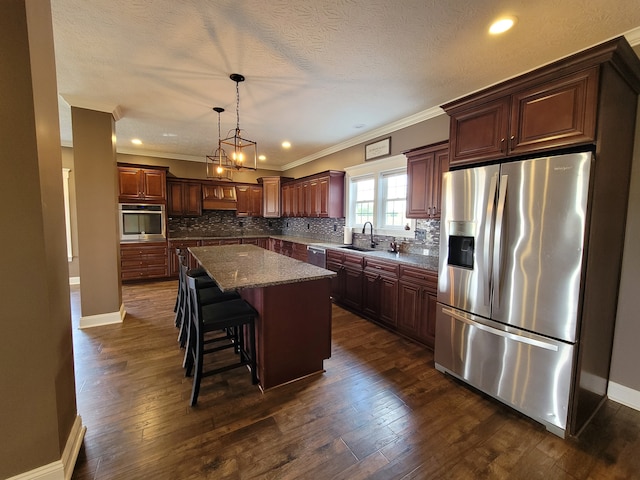 kitchen with dark hardwood / wood-style flooring, a textured ceiling, stainless steel appliances, sink, and a center island