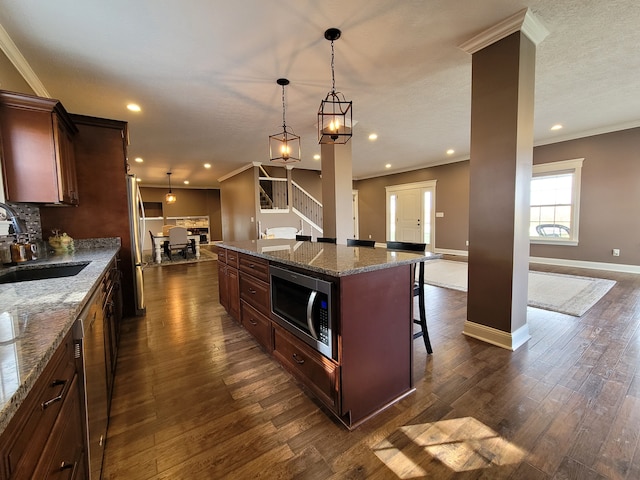 kitchen featuring sink, a center island, stainless steel appliances, decorative light fixtures, and a breakfast bar